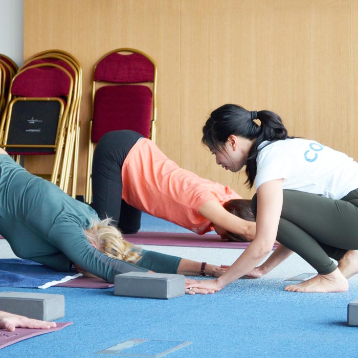 Photo d'une coach corrigeant la posture de Yoga d'une participante