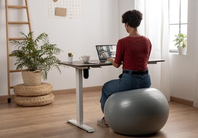Photo d'une femme assise à son bureau sur un ballon de gym