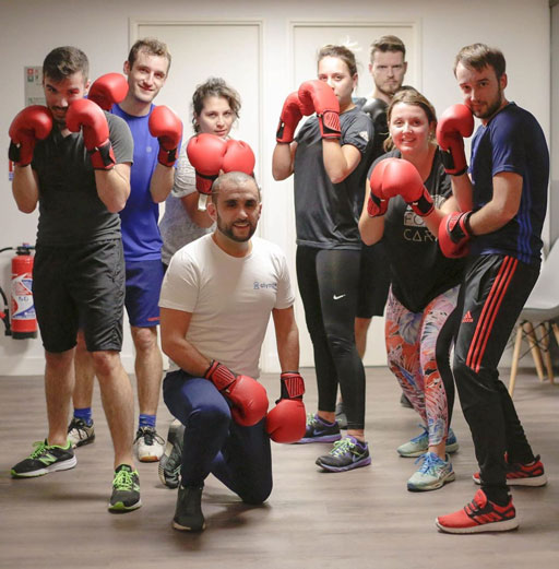 Photo du groupe de participants et de leur coach, en fin de séance de Boxe, avec de la bonne fatigue et des sourires