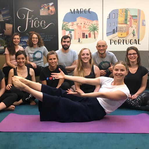 Photo en fin de séance de Pilates en entreprise : des employés souriants avec avec un coach Olympe